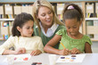 Kindergarten teacher sitting with students in art class