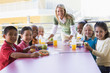 Kindergarten teacher supervising children eating lunch