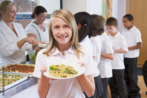 Photo: Schoolgirl holding plate of lunch in school cafeteria Schoolgirl holding plate of lunch in school cafeteria