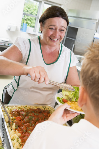 Photo: Lunchlady serving plate of lunch in school cafeteria Lunchlady serving plate of lunch in school cafeteria