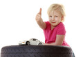 Foto: Little cute girl sitting on a tyre with toy car shows thumb up Little cute girl sitting on a tyre with toy car shows thumb up