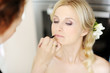 Young beautiful bride applying wedding make-up by make-up artist