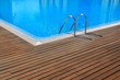 Photographie : blue swimming pool with teak wood flooring