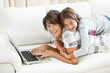 Mother and daughter using laptop and smiling
