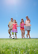Young girl playing football with family on grass