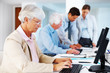 Busy old businesswoman working on computer at office