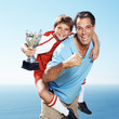 Excited father piggybacking his champion footballer son