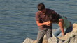 Young couple climbing on rocks overlooking the water