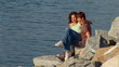 Young couple sitting on rocks overlooking the water