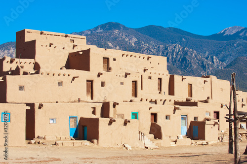 Photo: Ancient Taos Pueblo with mountains on background, New Mexico Ancient Taos Pueblo with mountains on background, New Mexico
