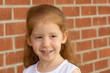 Photo: Portrait of Young redhead kid girl by brick wall Portrait of Young redhead kid girl by brick wall