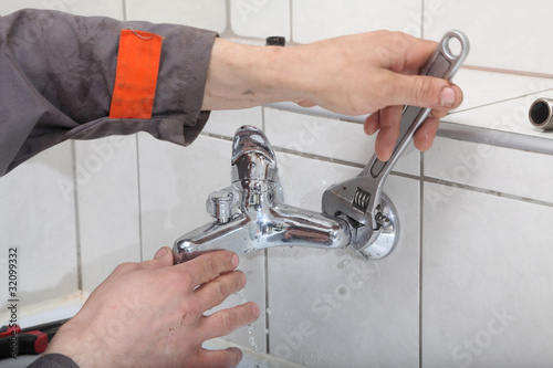 Foto: Plumber fixing water tap with spanner Plumber fixing water tap with spanner