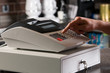 Foto: Closeup of a cashier's hand ringing cash register. Closeup of a cashier's hand ringing cash register.