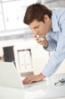 Young office worker on phone using computer