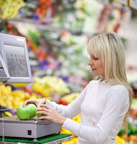 Photo: Beautiful young woman shopping for fruits and vegetables in prod Beautiful young woman shopping for fruits and vegetables in prod