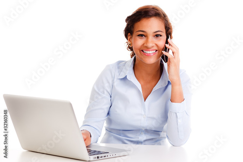 Foto: junge frau sitzt am computer beim telefonieren junge frau sitzt am computer beim telefonieren