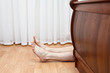 Bare hairy legs behind bed. Man lying on the floor in bedroom