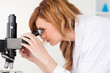 Attractive blond-haired scientist looking through a microscope