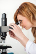 Cute blond-haired scientist looking through a microscope