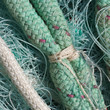Noeud blanc sur corde verte posée sur un filet de pêche.