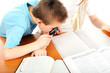 schoolboy with loupe on the table with exercise books