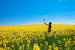 man with pinwheel standing in a field of yellow rape against the