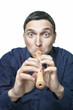 Funny young man trying to play block flute isolated on white