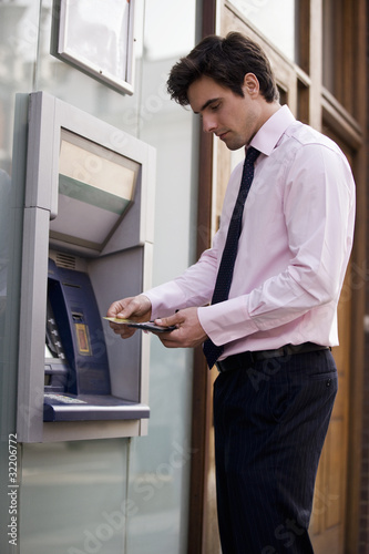 Photo: A businessman using a cash machine A businessman using a cash machine