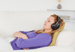 Good looking red-haired woman listening to music while taking a