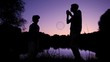 silhouettes of boy and man blowing up soap bubbles near lake