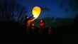 man does some attempts to start chinese lantern, family look