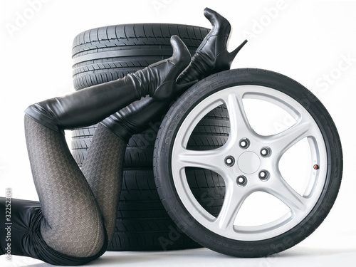 Foto: Sexy woman with High Heels playing with set of summer tyres Sexy woman with High Heels playing with set of summer tyres
