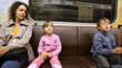 mother with daughter and son sit in riding subway train