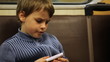 boy sits and studies yawning ticket in moving subway train