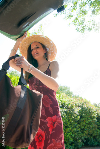 Photo: jeune femme qui met un sac dans le coffre jeune femme qui met un sac dans le coffre