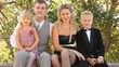 Family in celebratory clothes sits on a bench in summer day.