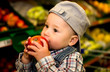 kleiner Junge isst Apfel im Supermarkt