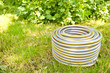 Grey plastic water hose on green grass