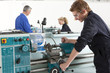 Teacher talking to students using lathe in vocational school