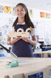 Proud student holding wooden carving in vocational school classroom