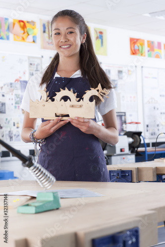 Photo: Proud student holding wooden carving in vocational school classroom Proud student holding wooden carving in vocational school classroom