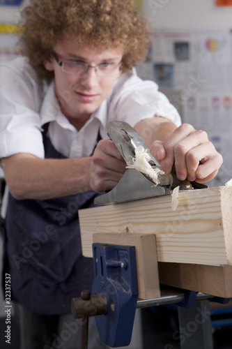 Photo: Serious student planing wood in vocational school Serious student planing wood in vocational school
