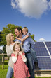 Happy family standing near large solar panels