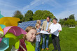 Technician holding blueprints talking to family near large solar panels