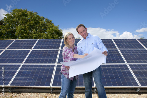 Foto: Technicians holding blueprints talking near large solar panels Technicians holding blueprints talking near large solar panels