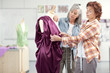 Designers assessing evening gown on dressmaker's dummy in classroom