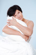 Smiling beautiful woman sitting on her bed with pillow