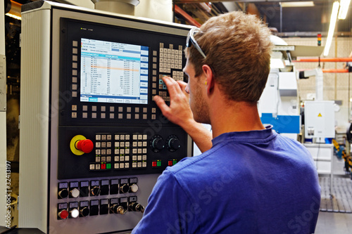 Photo: skilled worker controlling a digitally programmed machine tool skilled worker controlling a digitally programmed machine tool