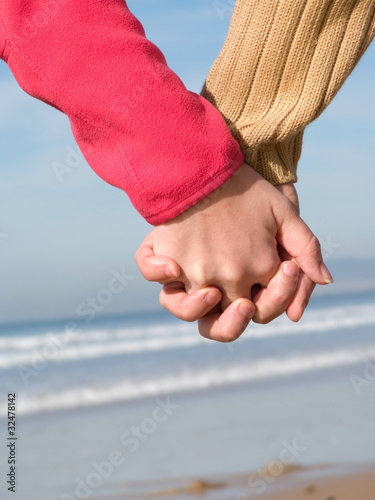 couple holding hands on beach. Lovers couple holding hands on each at winter