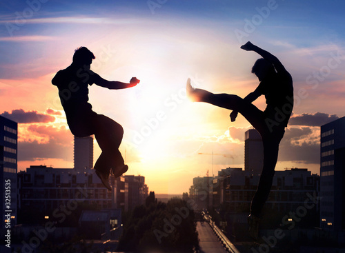 Foto: Two capoeira fighters over city background Two capoeira fighters over city background